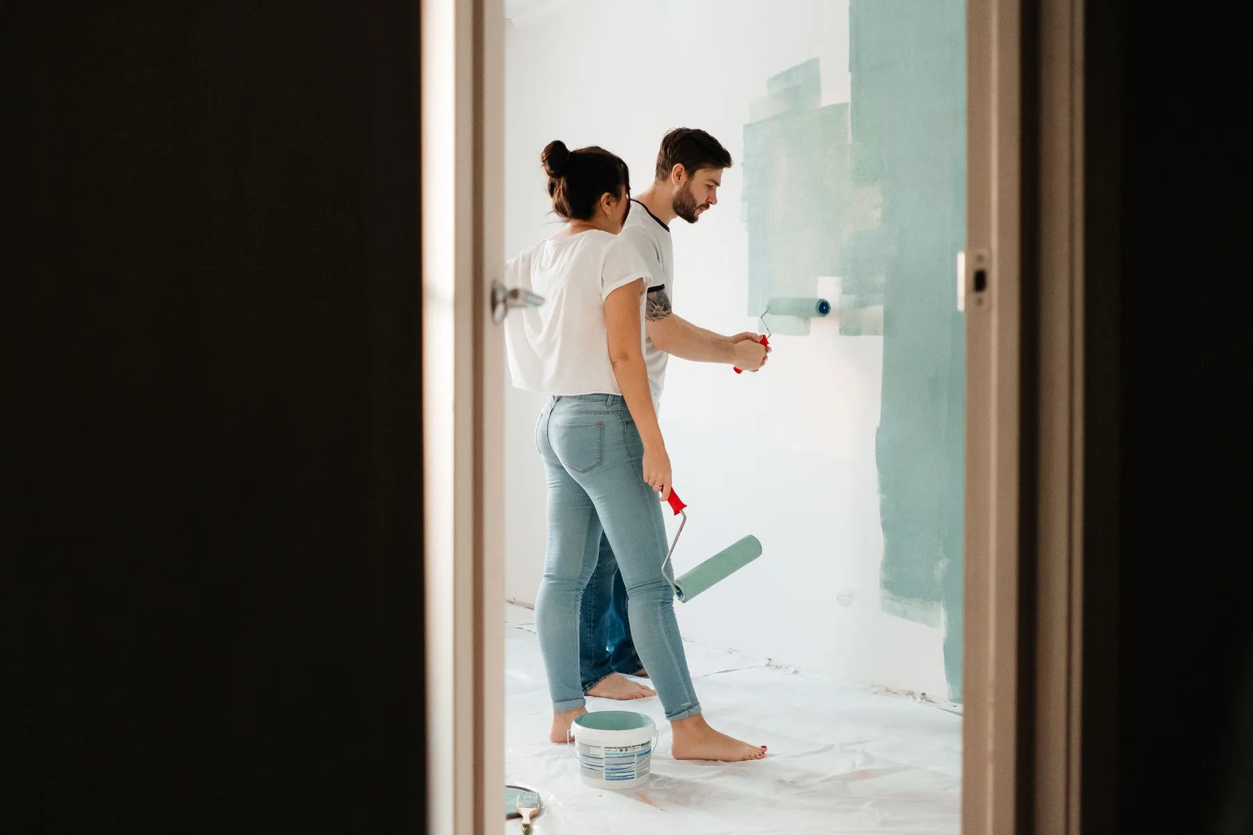 Echipa aplicand vopsea pe perete interior intr-o renovare.